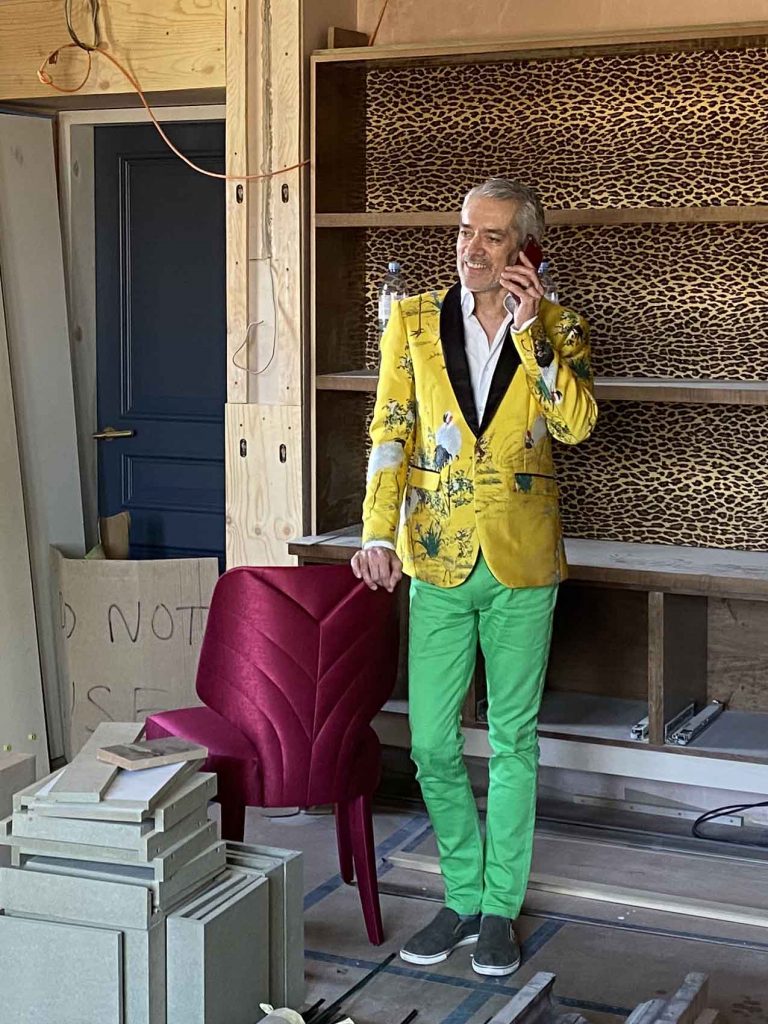 Top London interior designer, Rene Dekker in Yellow blazer and green trousers in study